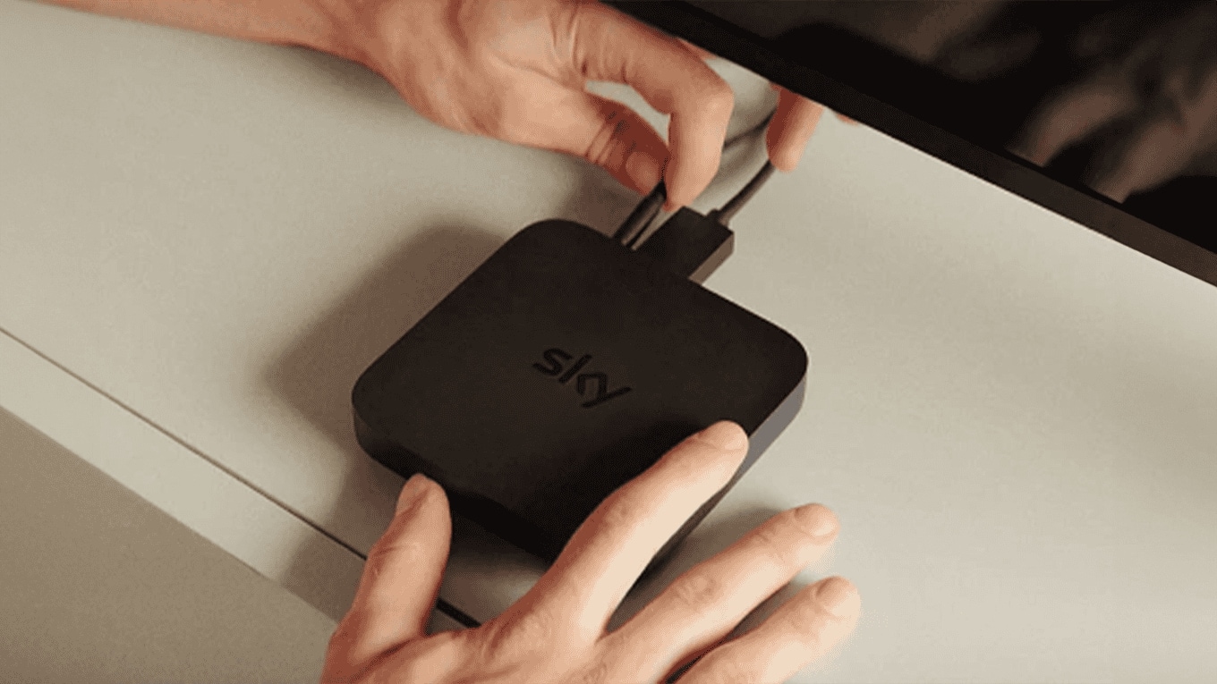 Menschliche Hände, die den zugehörigen Netzstecker an die Sky Stream Box anschließen.